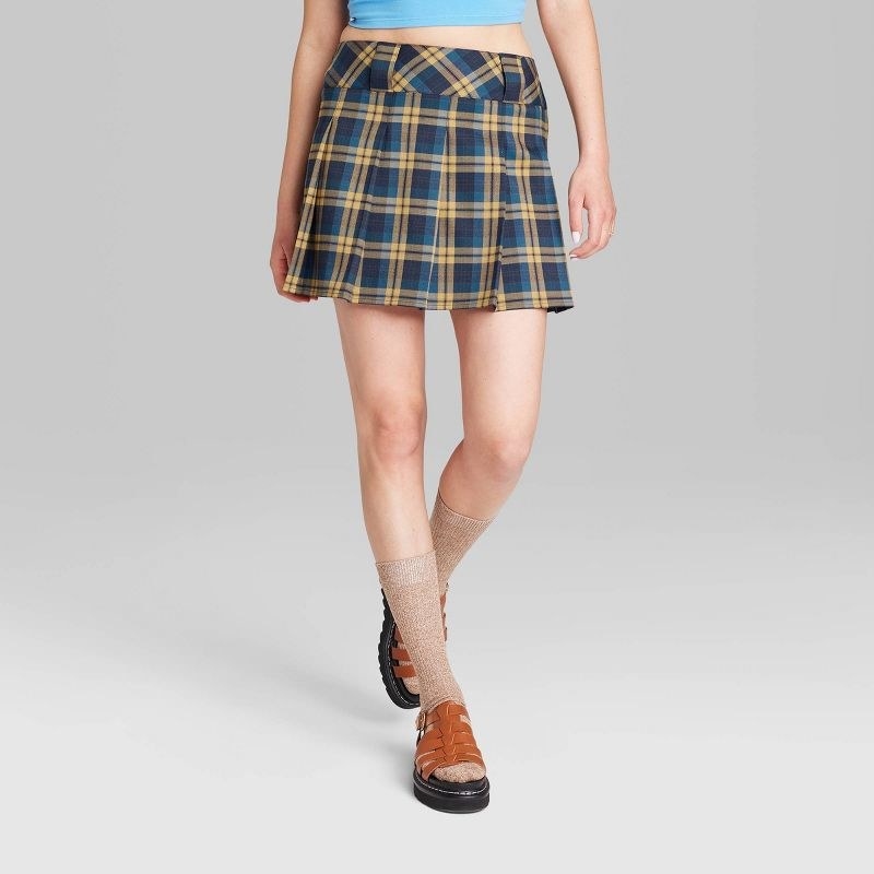 model wearing blue and yellow plaid pleated mini skirt