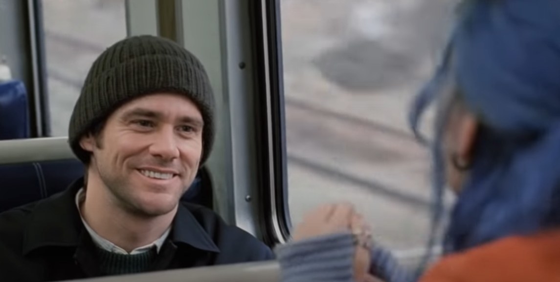 Jim Carrey as Joel Barish talking to someone on a train