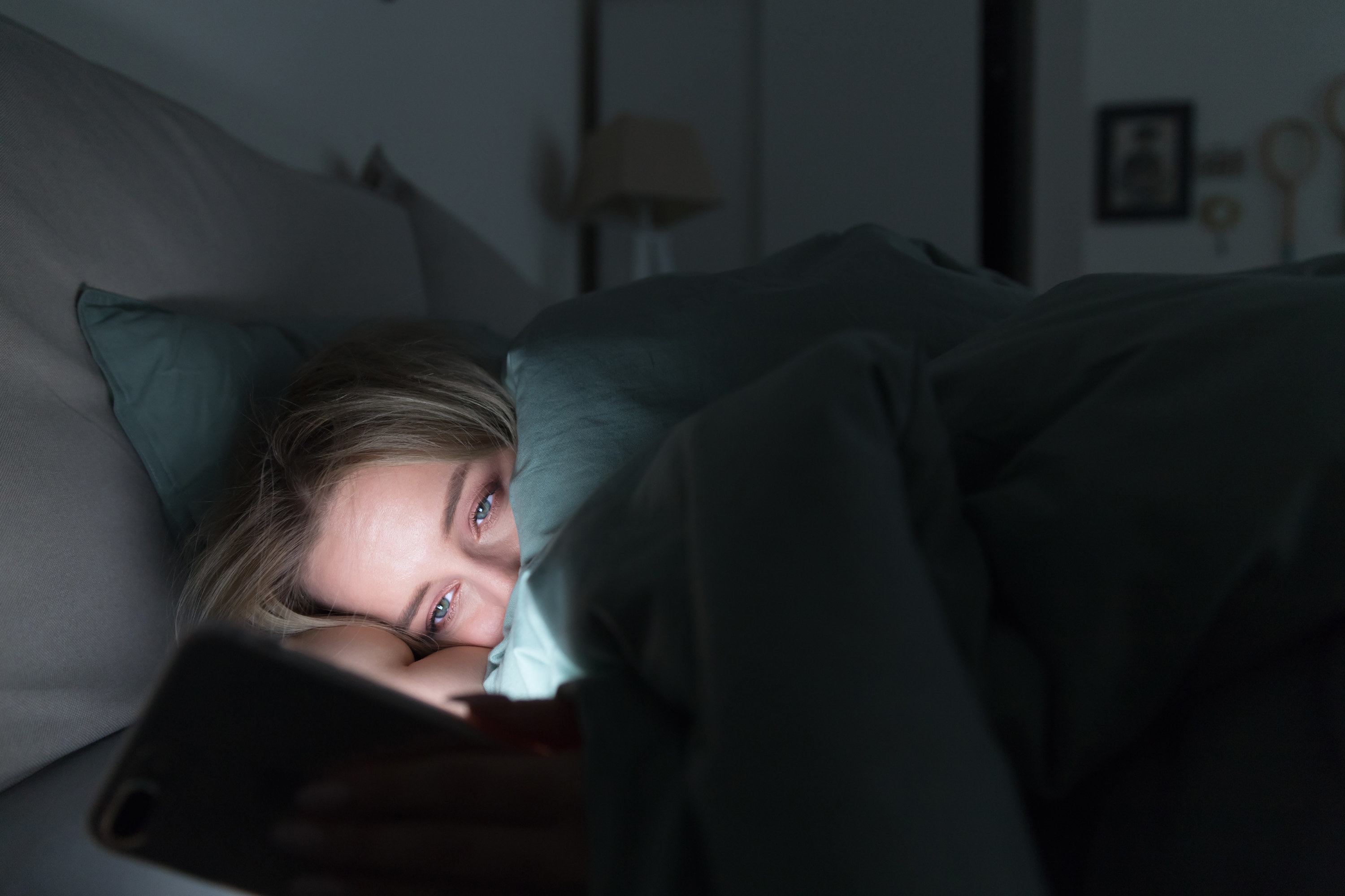 woman looking at her phone in bed