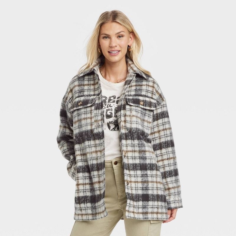 model wearing white, gray, and yellow plaid shacket and beige cargo pants