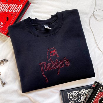 black sweatshirt embroidered with red lettering that reads Nadja's
