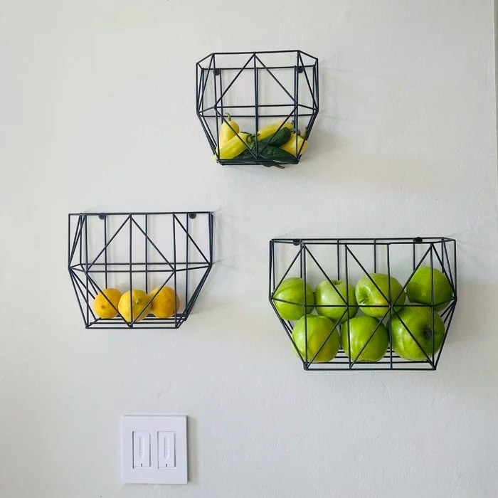 Three fruit baskets holding yellow peppers, lemons, green apples