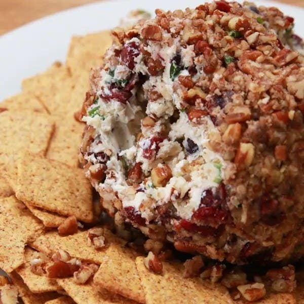 Cheese ball encrusted in pecans and cranberries with wheat crackers