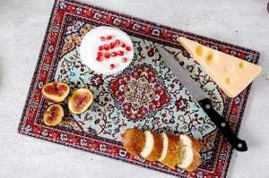 the red and blue cutting board with cheese and figs on it 