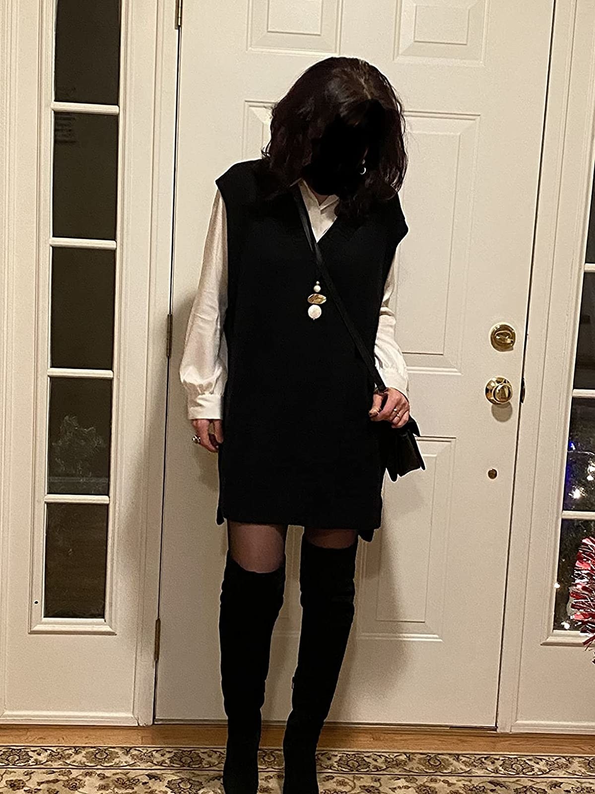 A reviewer wearing black oversized sweater dress over a white shirt with black shoes