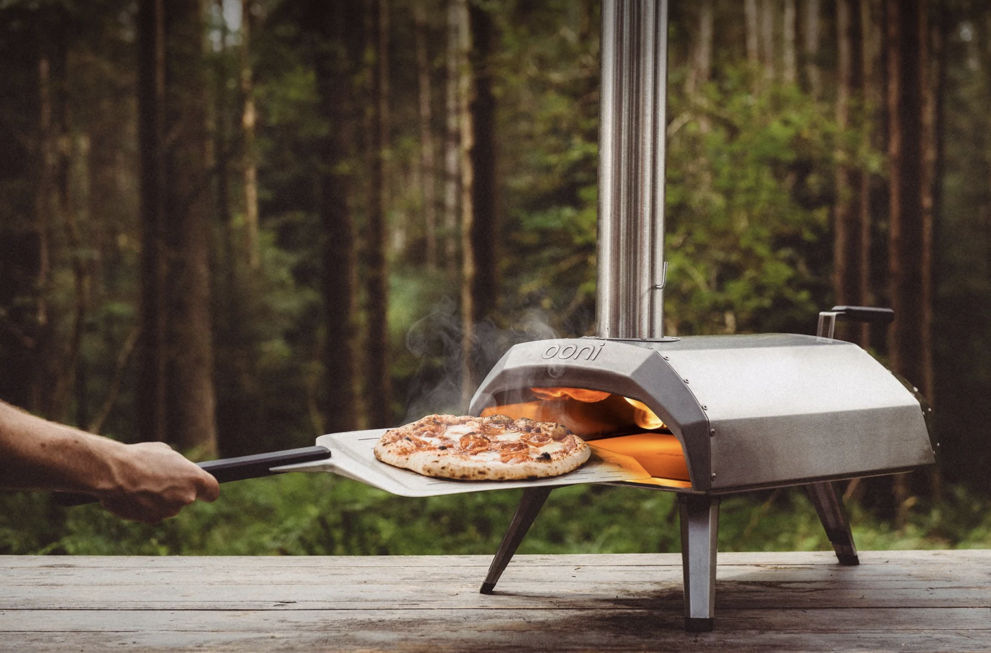 The metal pizza oven with a cooked pizza being pulled out of it