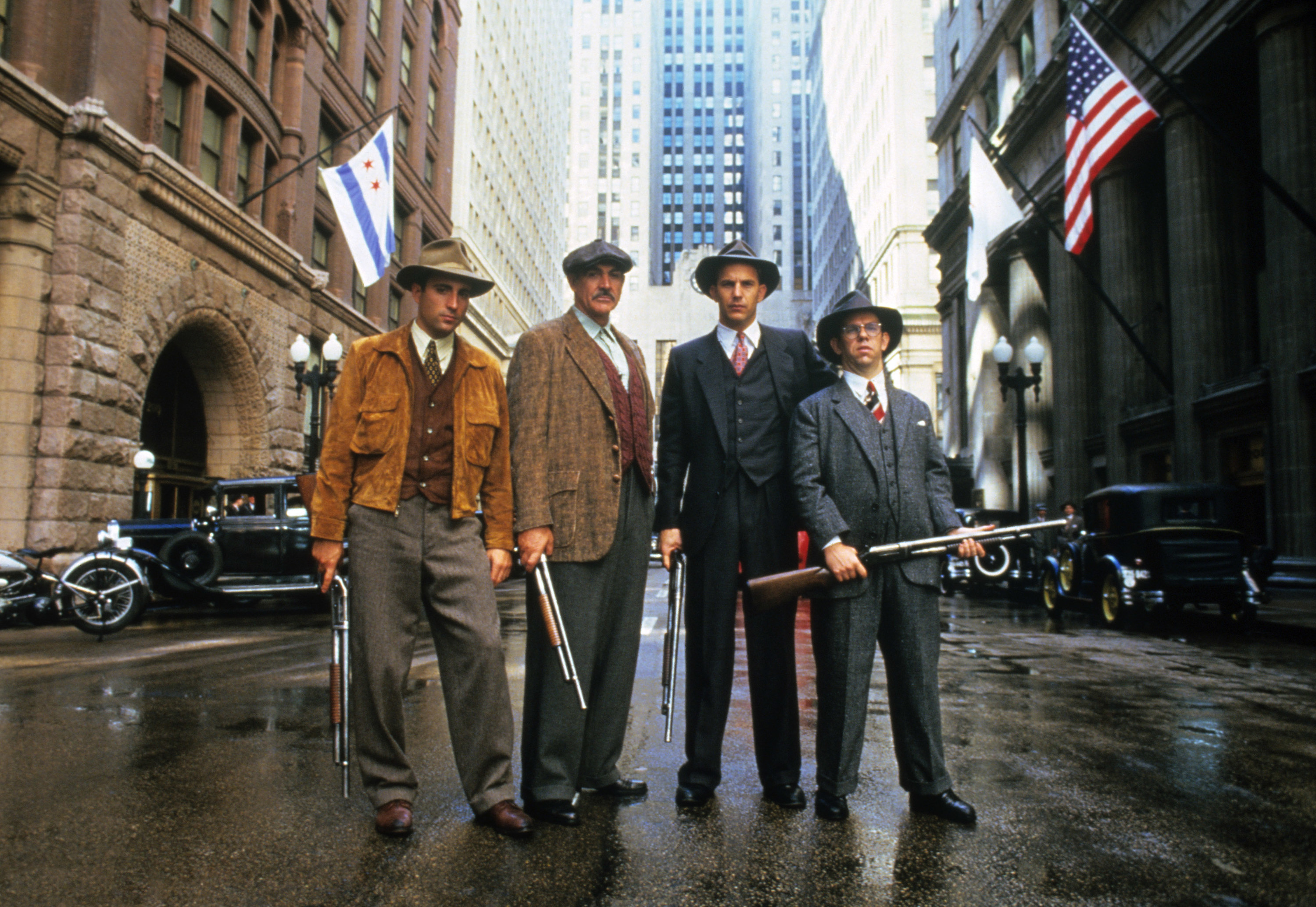 A group of men stand in the street, holding guns