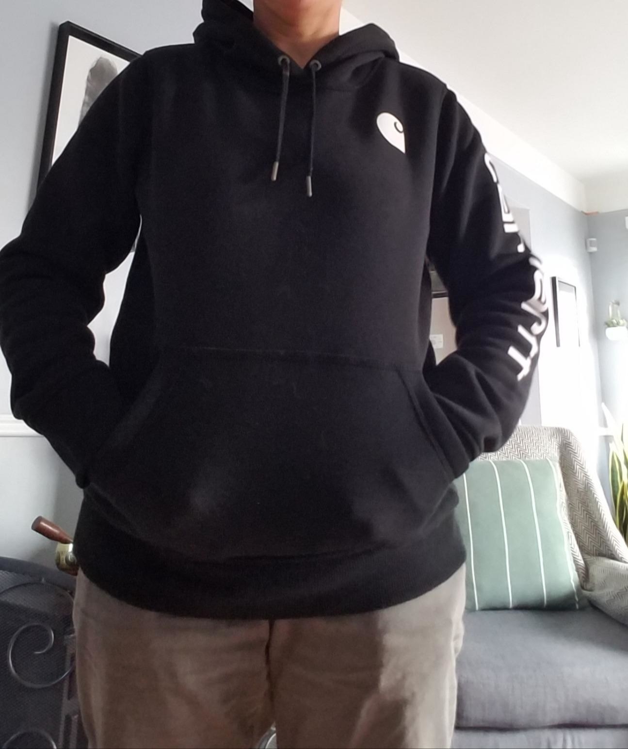 A reviewer wearing a black hoodie with brown pants