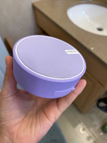 image of reviewer's hand holding purple speaker