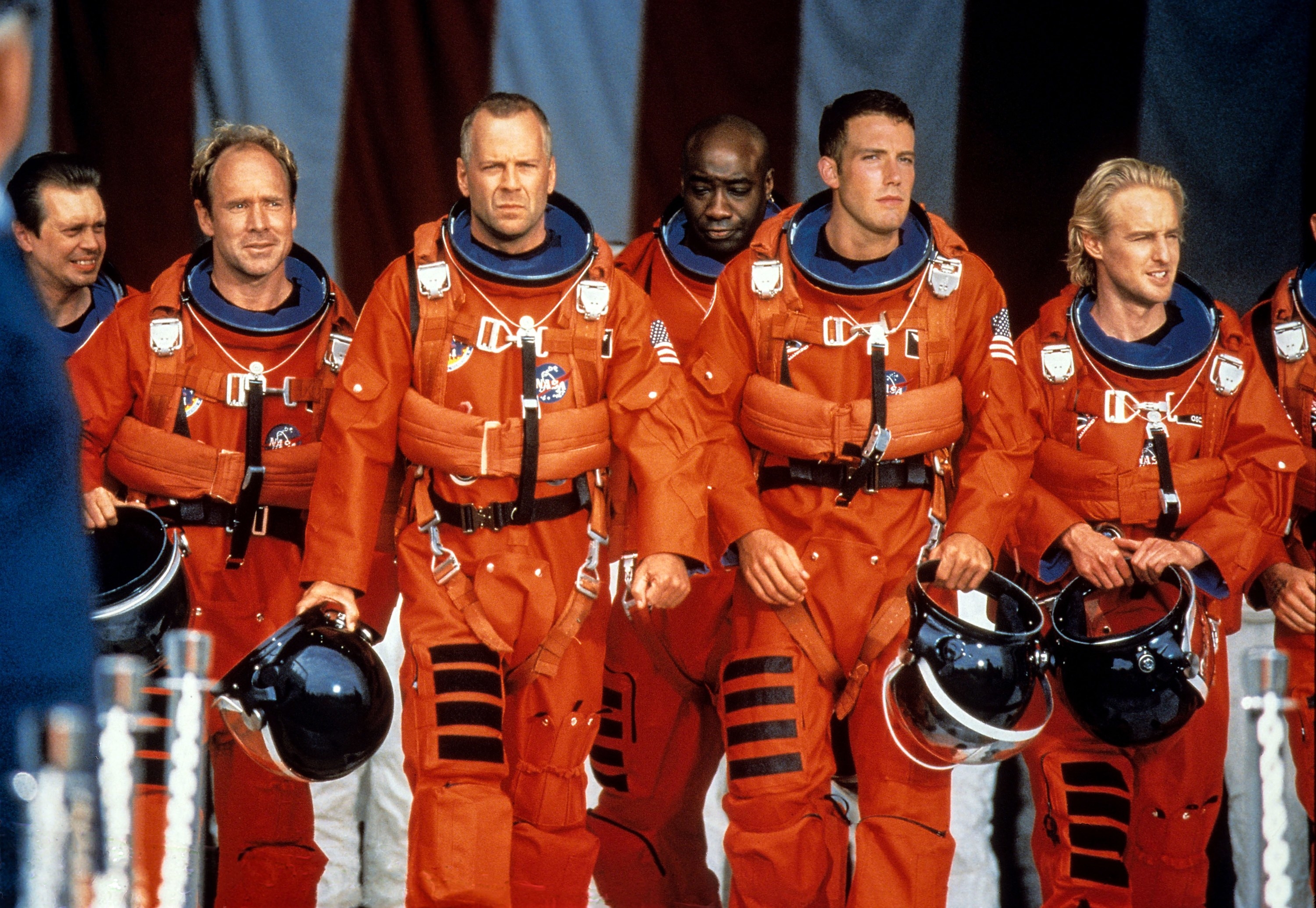 A group of men in astronaut uniforms walk toward a shuttle