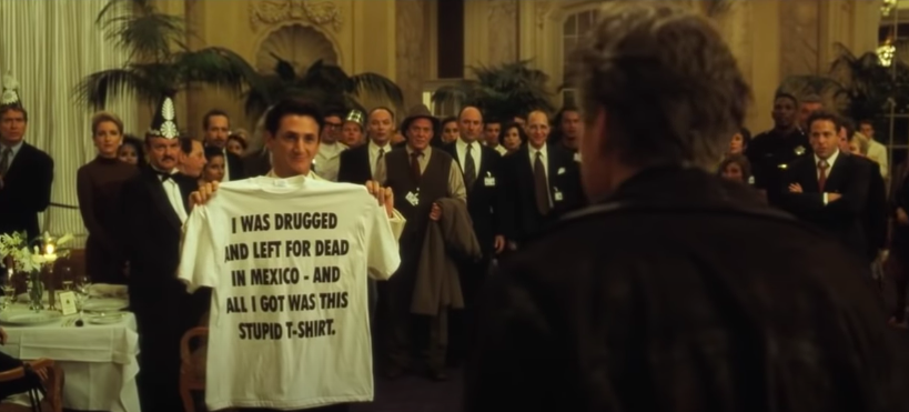 A man holding a shirt that reads &quot;I was drugged and left for dead in Mexico and all I got was this stupid shirt&quot;