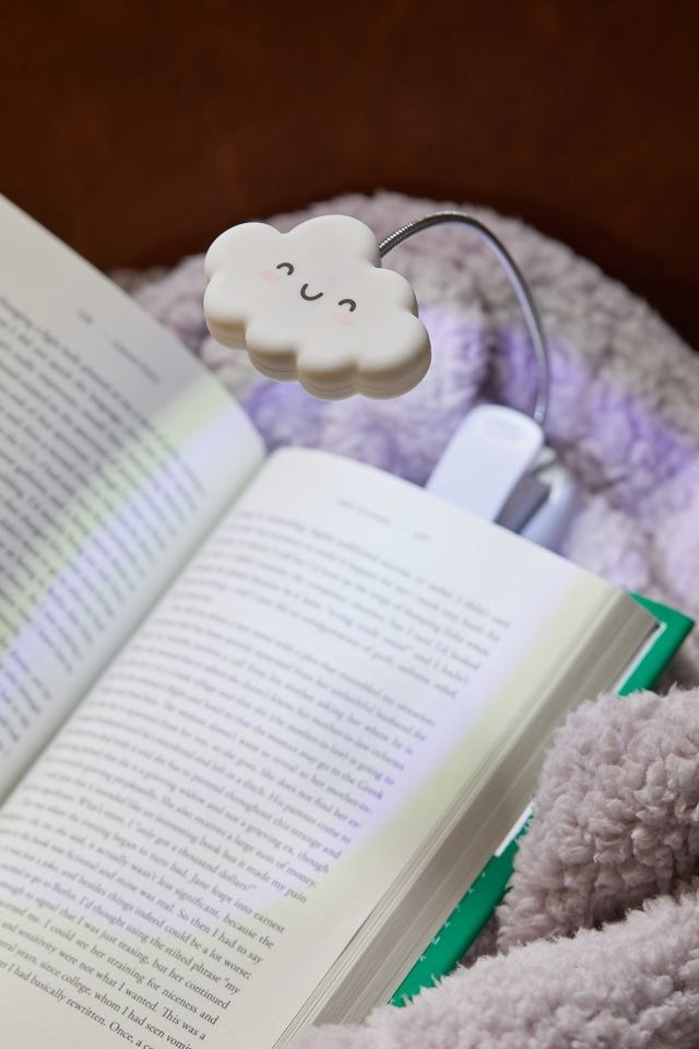 a cute cloud-shaped book light clipped onto a novel