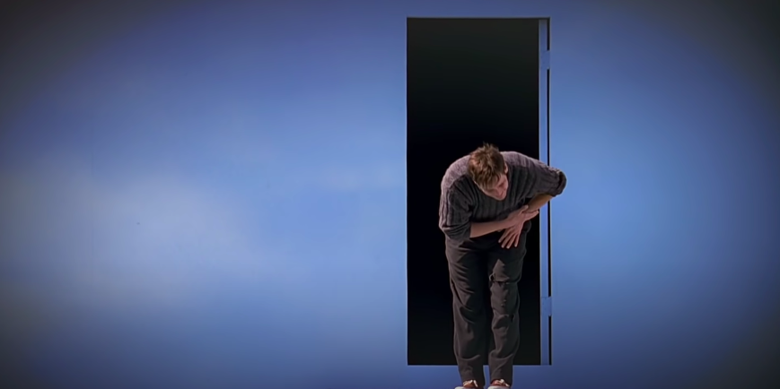 A man bows beside an open door