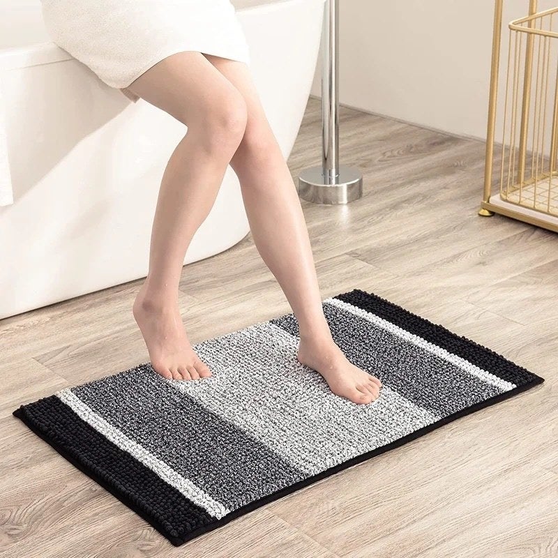 a black, gray, and white non-slip rug on a bathroom floor