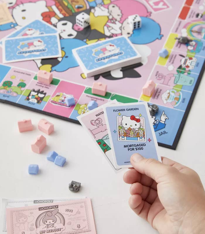 A person holding up cards for the Monopoly game