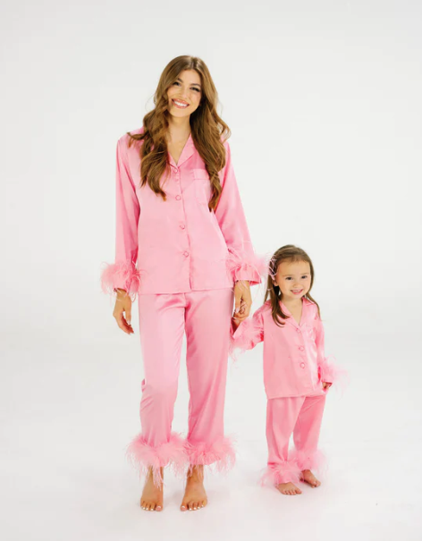 a mom and daughter in matching pink pajama pants and tops with pink feather cuffs on the wrists and ankles