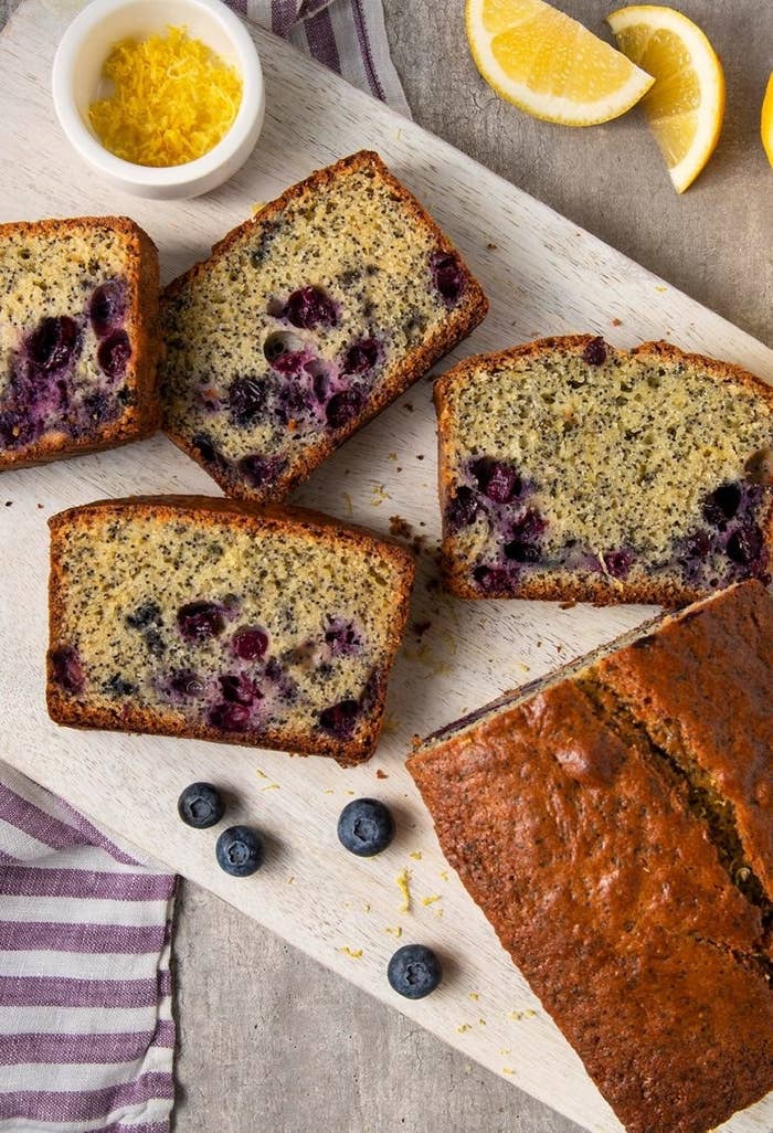 Four slices of blueberry lemon poppyseed bread sit on a tray beside a loaf