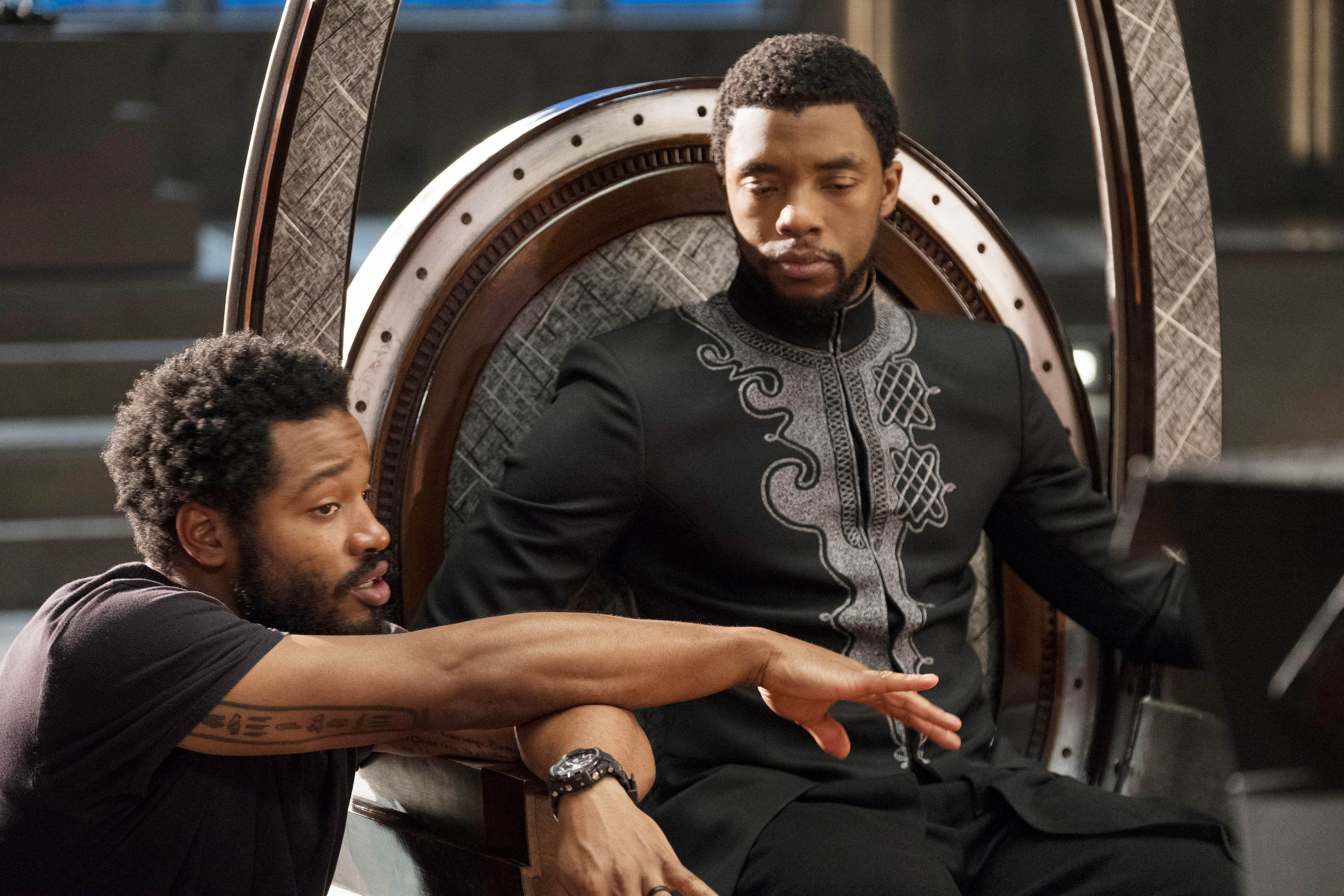 Ryan Coogler kneeling next to Chadwick who&#x27;s sitting the throne while discussing a scene