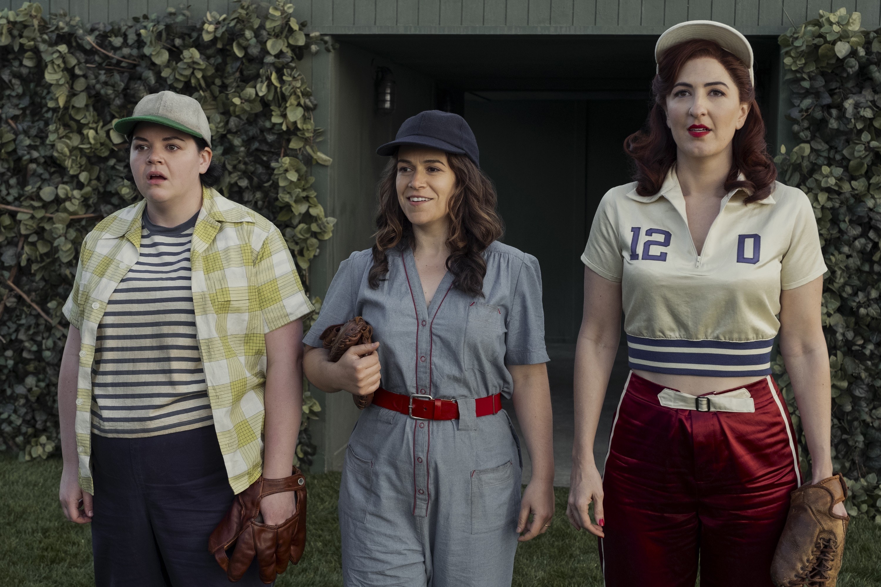 Melanie Field, Abbi Jacobson, and D&#x27;Arcy Carden stand outside wearing 1940s baseball/workout clothes in A League of Their Own.