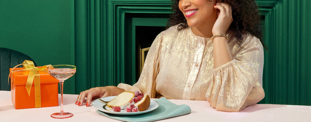 woman smiling with a plate of food, a martini glass, and a present