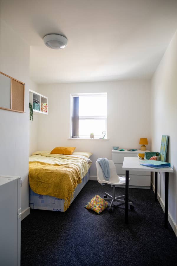 University bedroom in the North East of England. There is a single bed, a desk and no people.