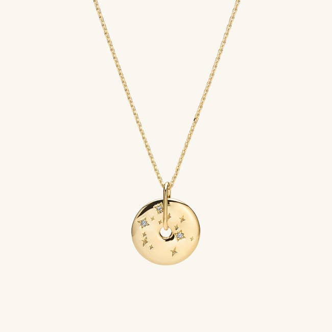 The gold pendant shaped like a donut with a constellation on it, hung from a chain