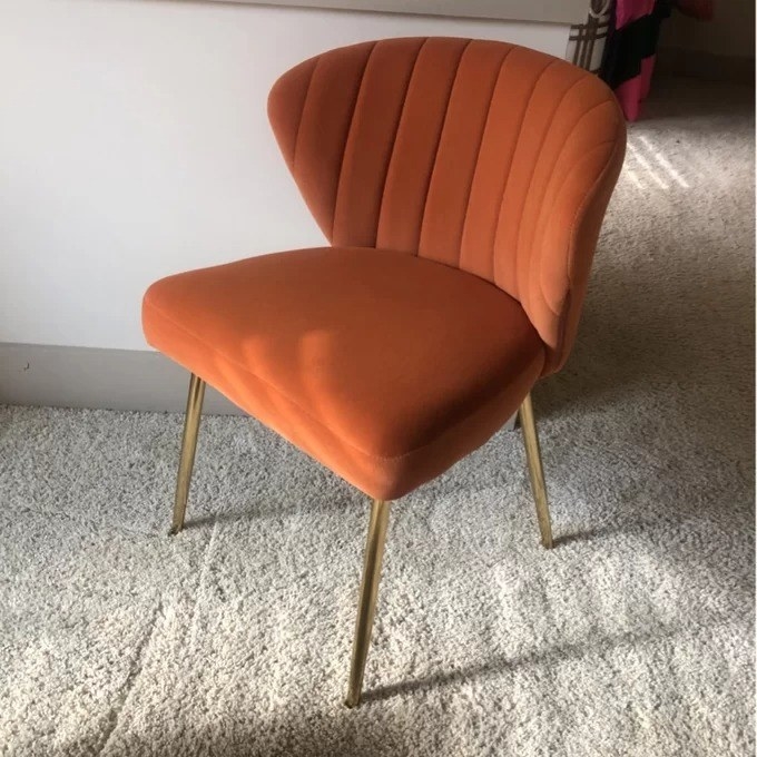 a reviewer photo of the orange chair with gold legs