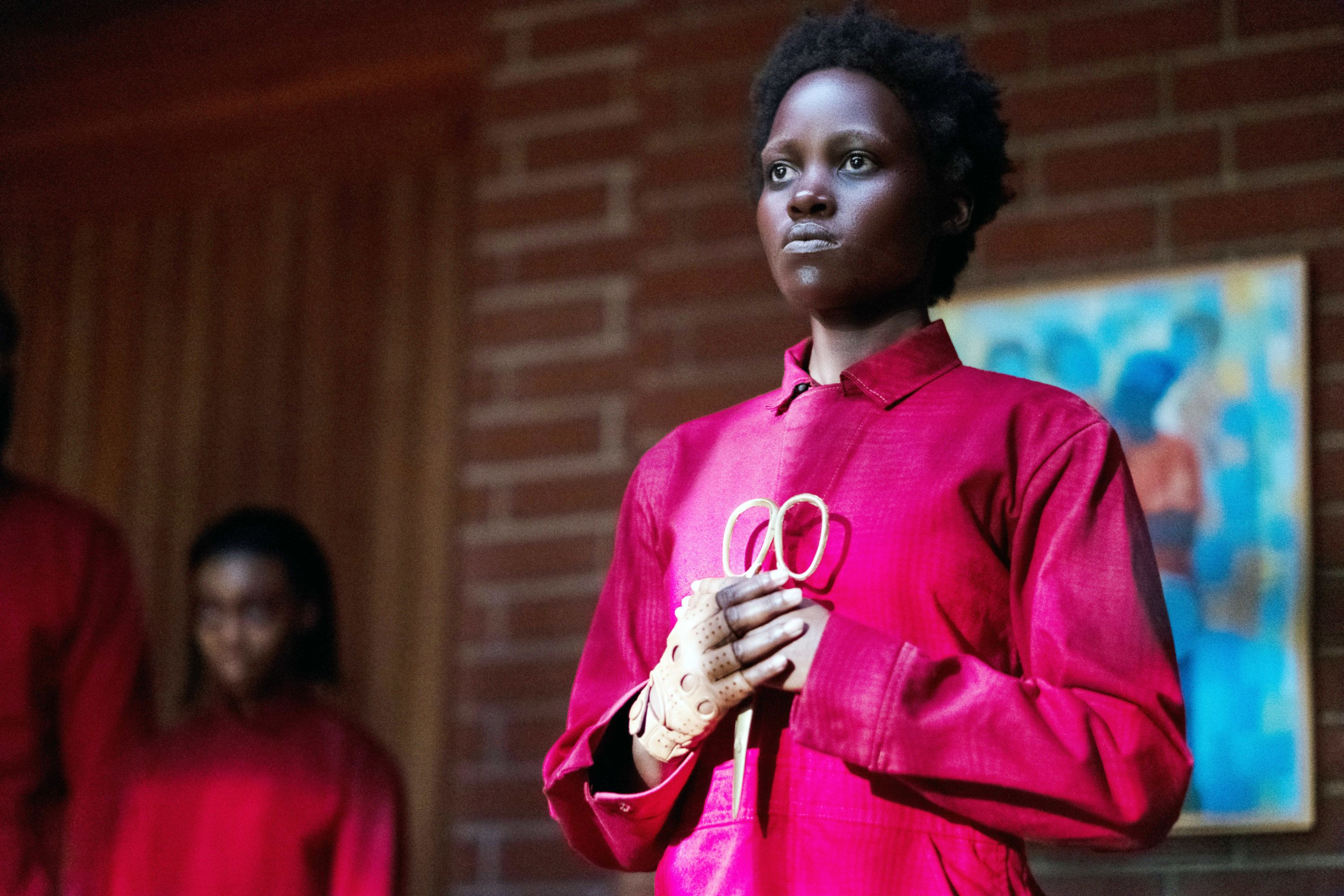 Lupita Nyong&#x27;o in Us holding a pair of scissors