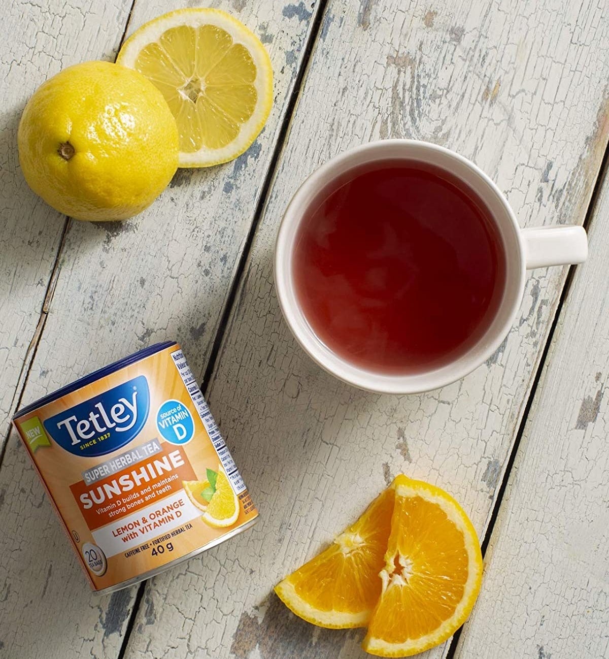 a container of tea bags next to a slices of orange and lemon and a cup of tea