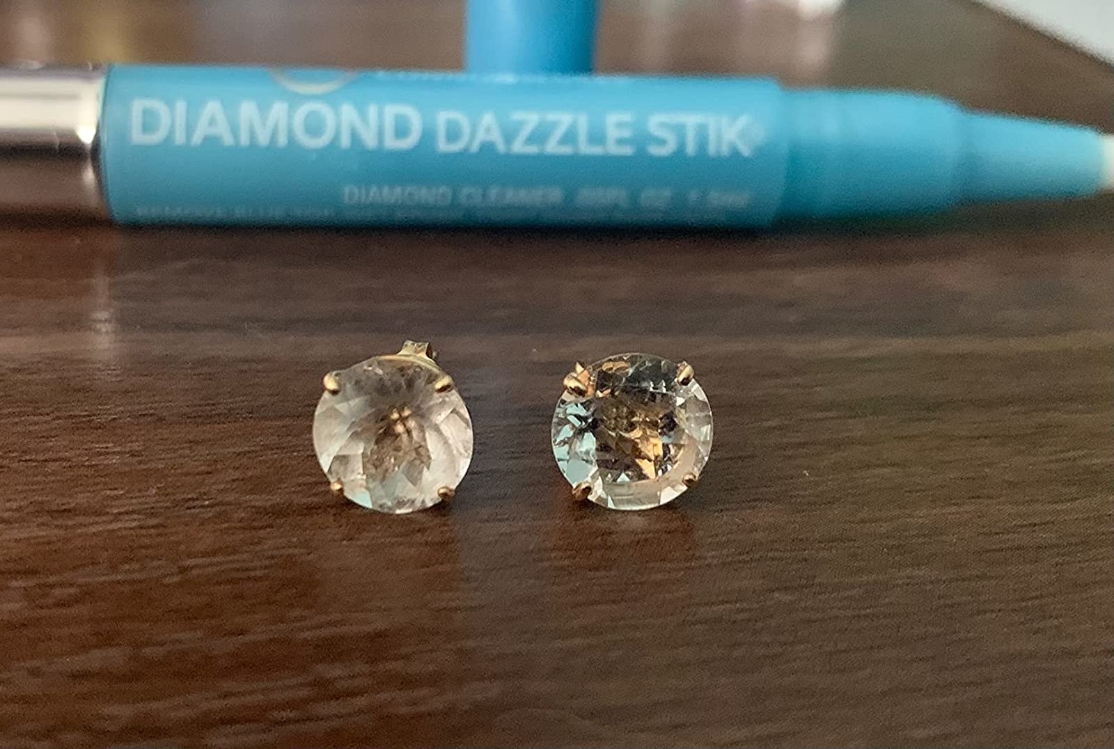 Reviewer&#x27;s diamond earrings, one visibly not cleaned and one sparkling clean after using the diamond stick