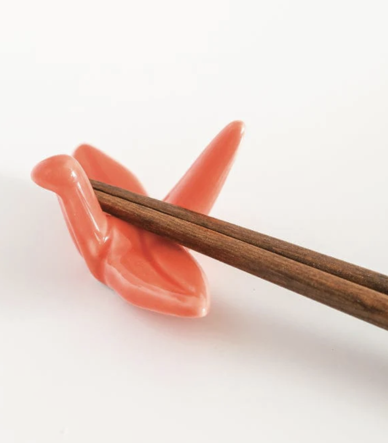 a pair of chopsticks resting on a crane-shaped holder