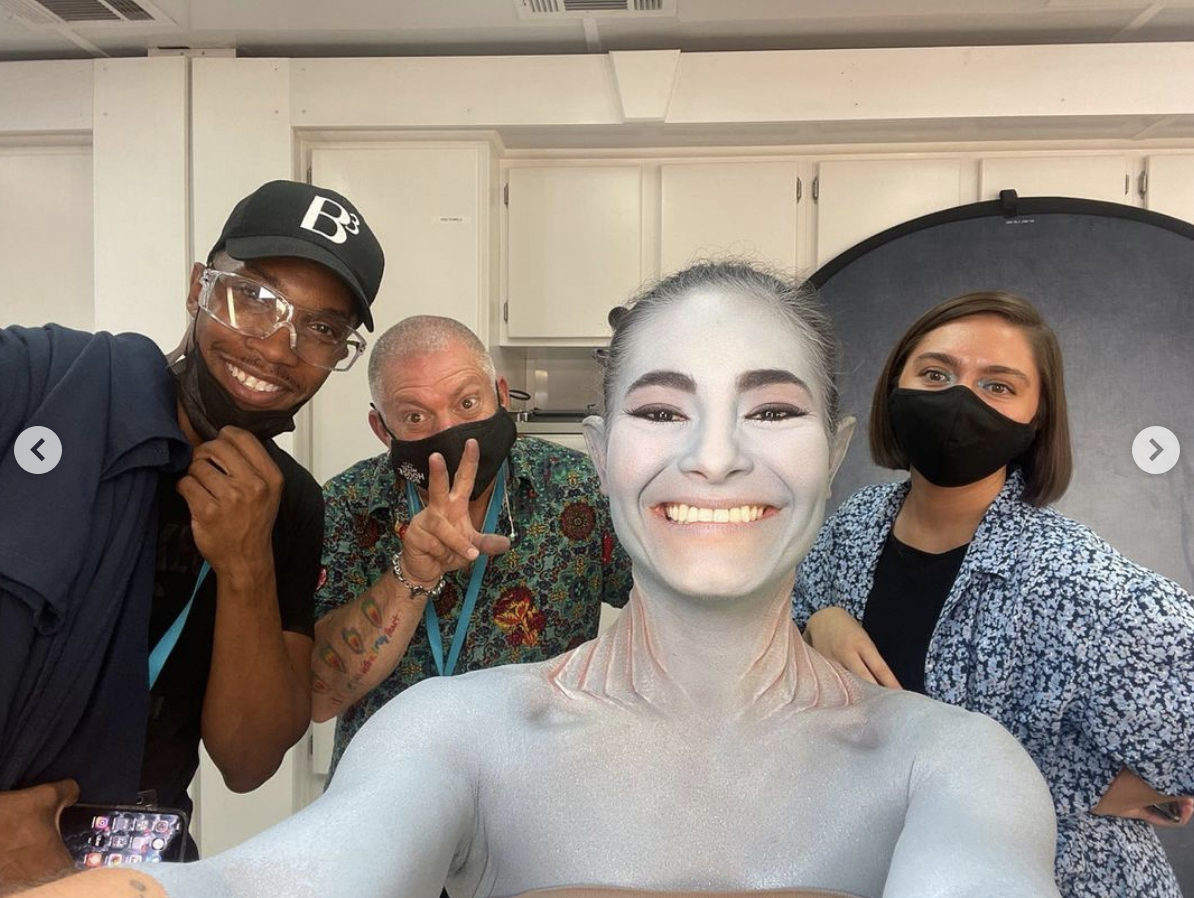 Mabel smiling with makeup artists and stylists behind her
