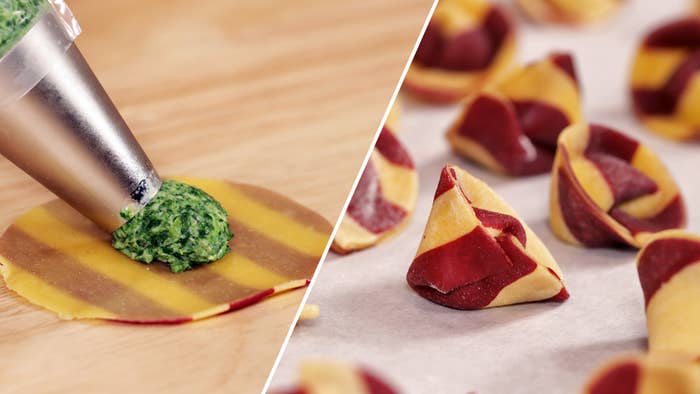 Red striped pasta with green pesto filling folded into shapes on a baking sheet