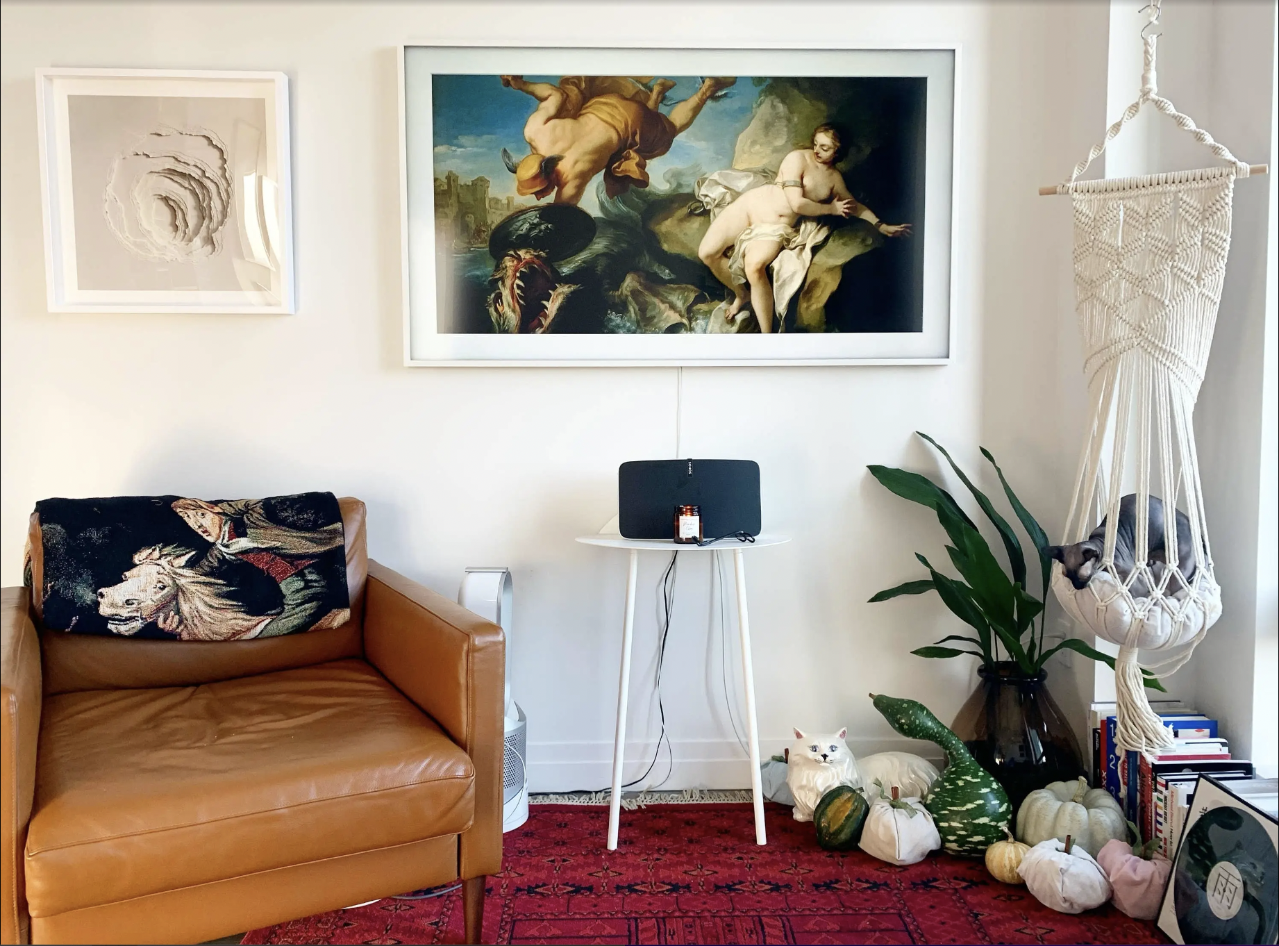 The white framed television in mounted on a wall displaying a painting