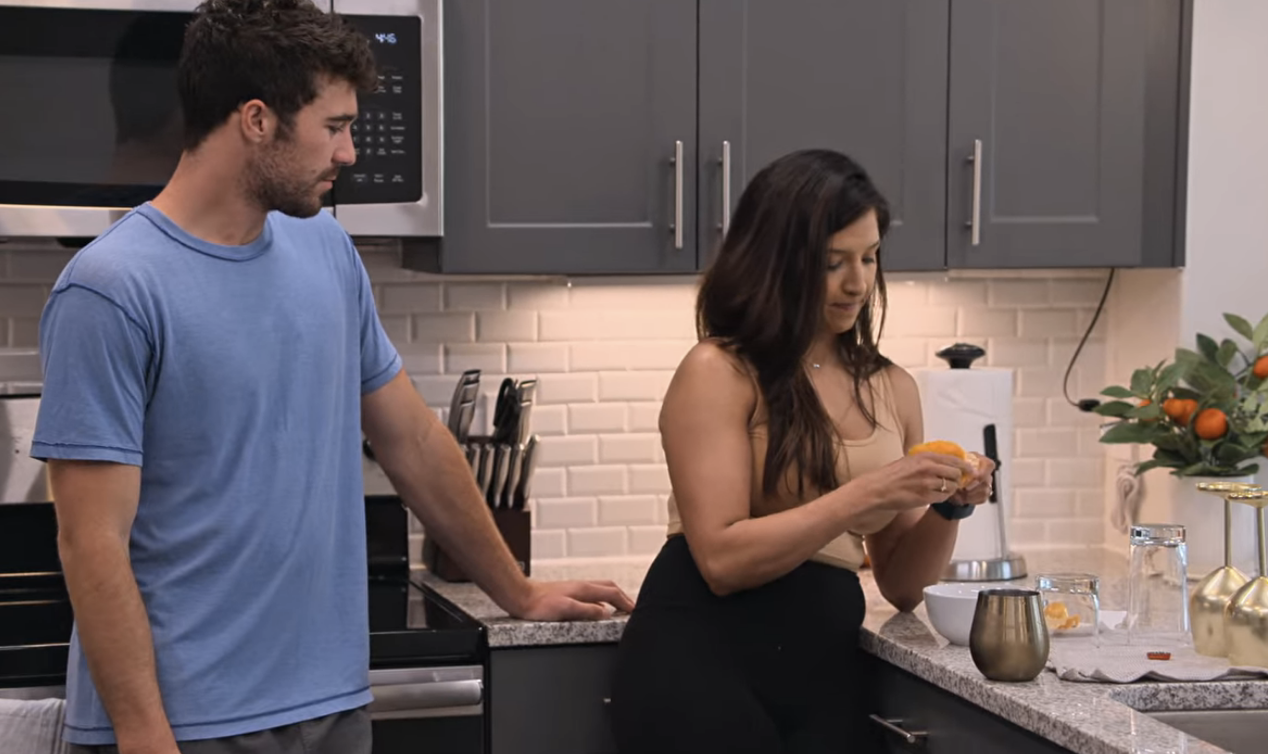 cole anf zanab in the kitchen as she peels an orange