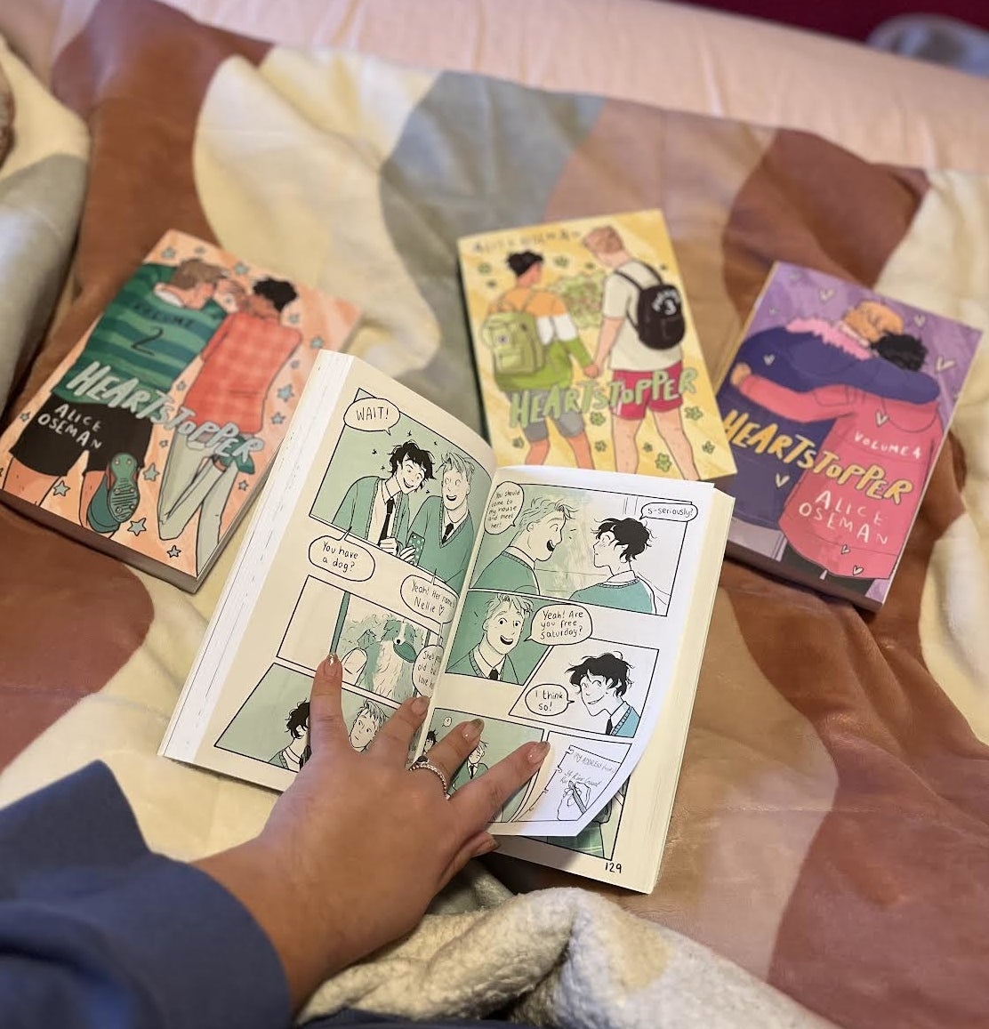 a photo of Bianca reading the graphic novel in bed surrounded by the other volumes