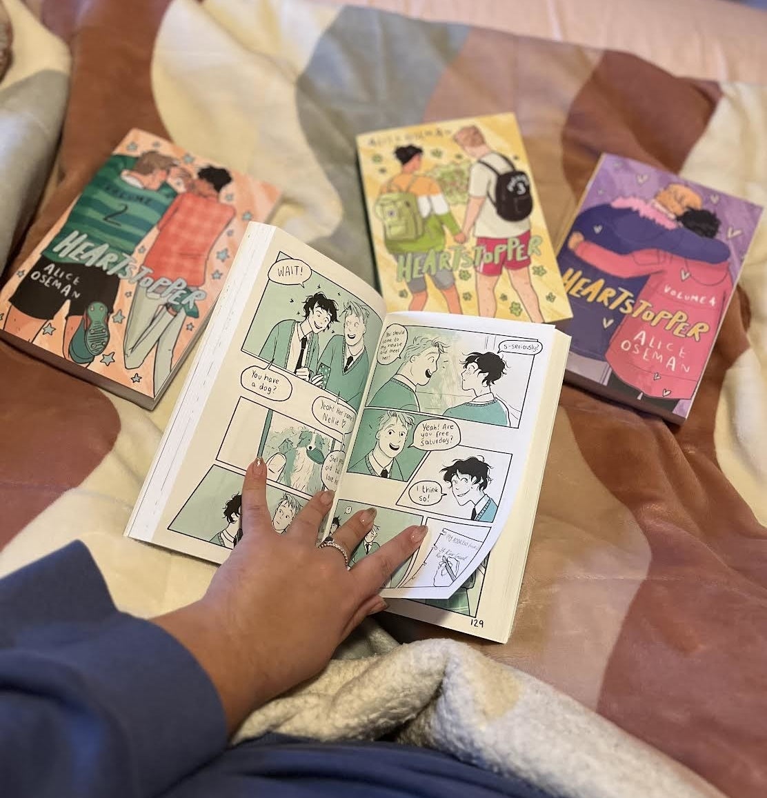 a photo of Bianca reading the graphic novel in bed surrounded by the other volumes