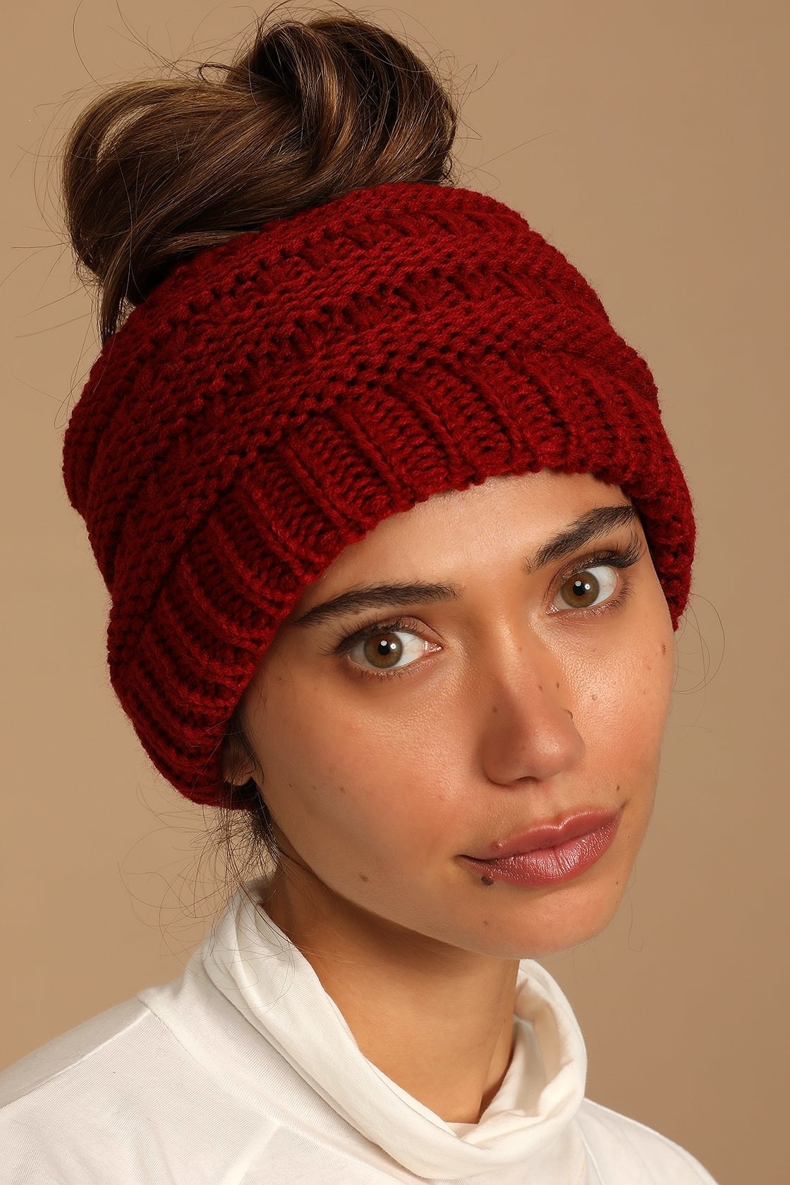 Model wearing red knit bun beanie