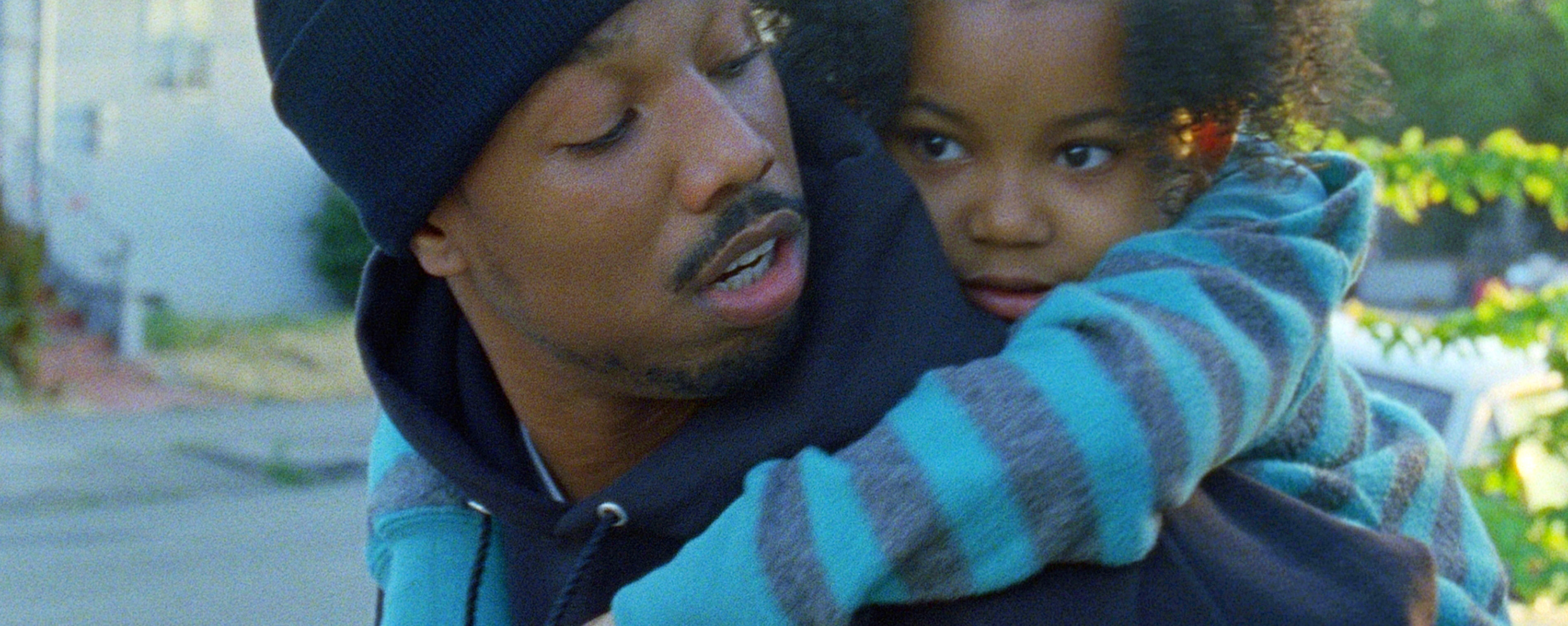 Michael B. Jordan in Fruitvale Station with a child hanging onto his shoulders and resting on his back