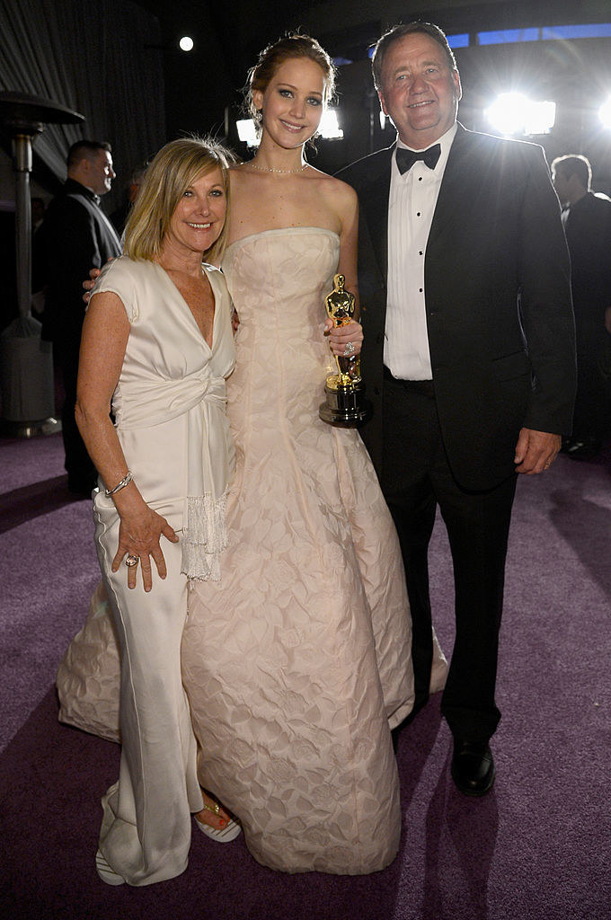 jennifer posing with her award with her parents on each side