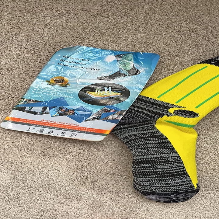 Reviewer photo of black and yellow sock next to pamphlet