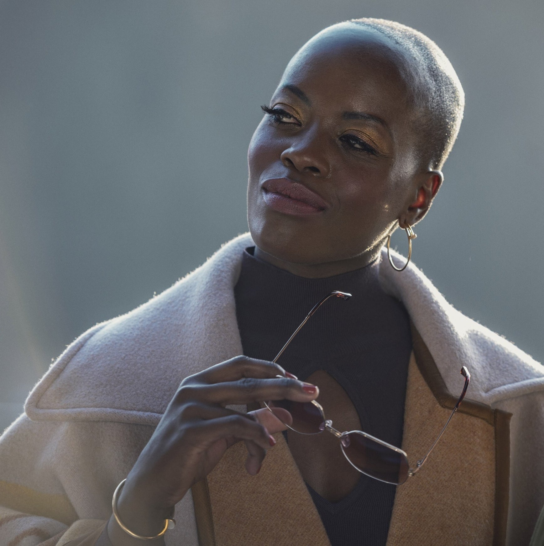 Florence Kasumba in Kitz holding a pair of sunglasses