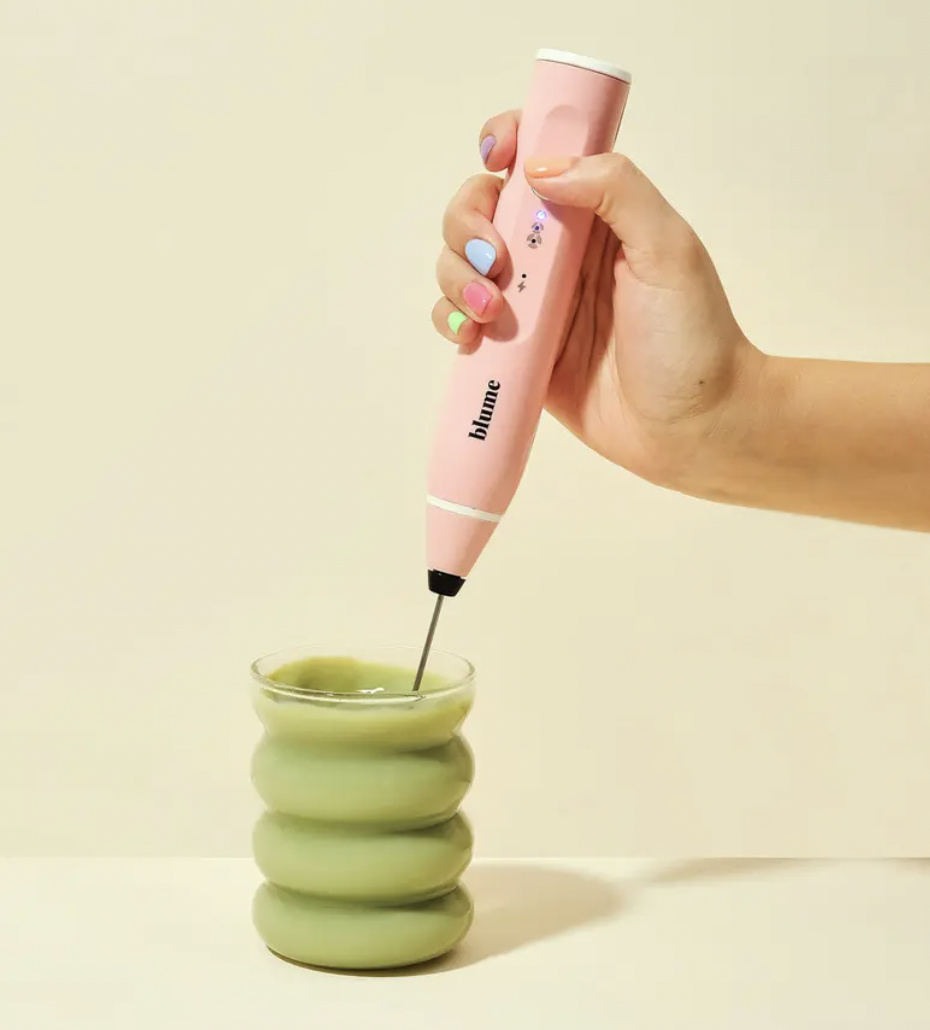 a person using the milk frother to whisk up matcha