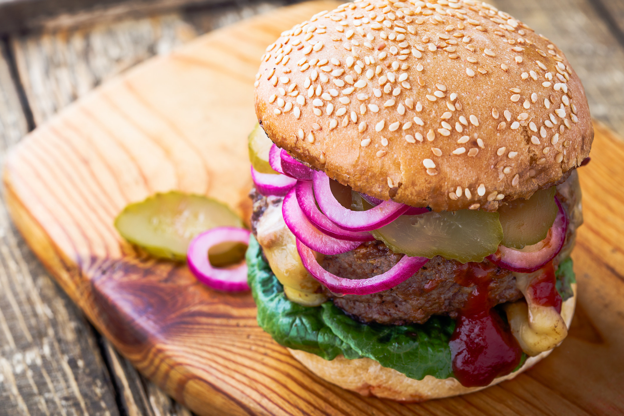 A burger topped with pickled red onions.