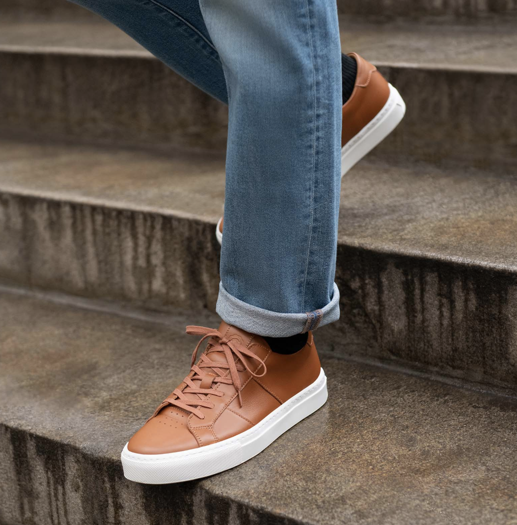 person wearing tan leather greats while walking down steps