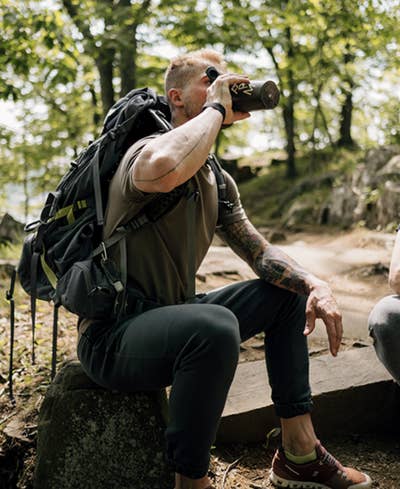 A hiker drinking a protein shake in nature