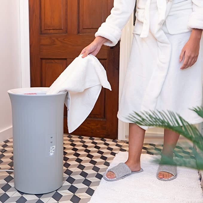 person taking towel out of circular-shaped warmer in grey