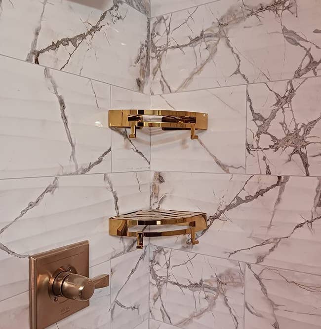 a reviewer photo of the gold shelves installed in a marble shower