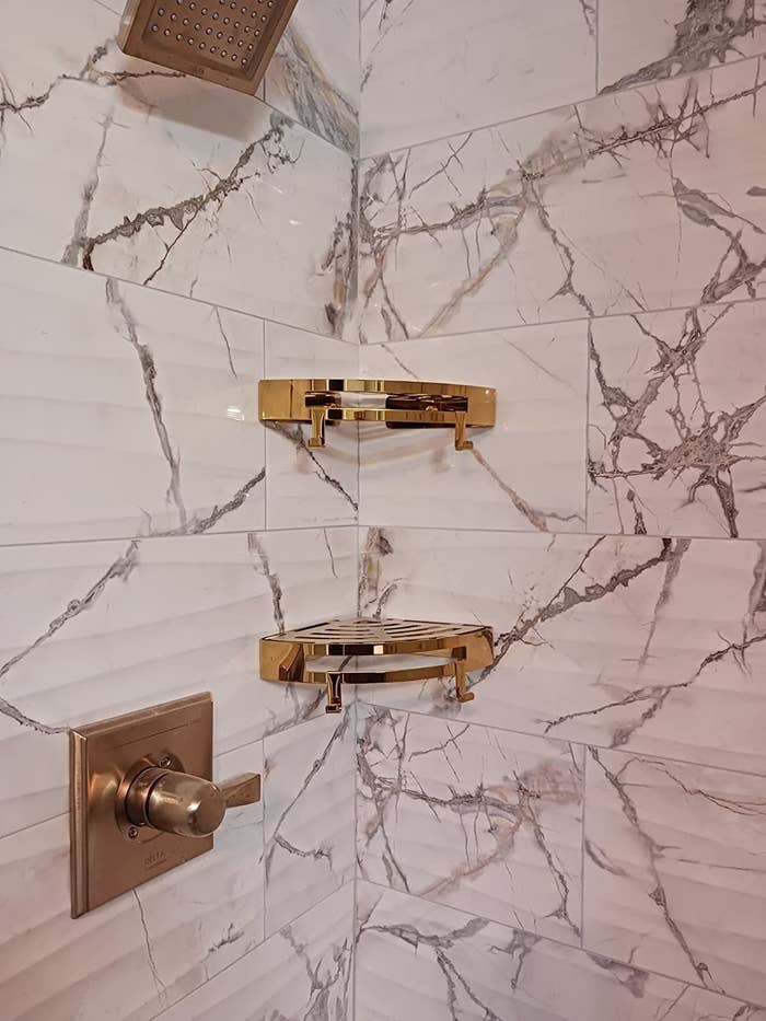 a reviewer photo of the gold shelves installed in a marble shower