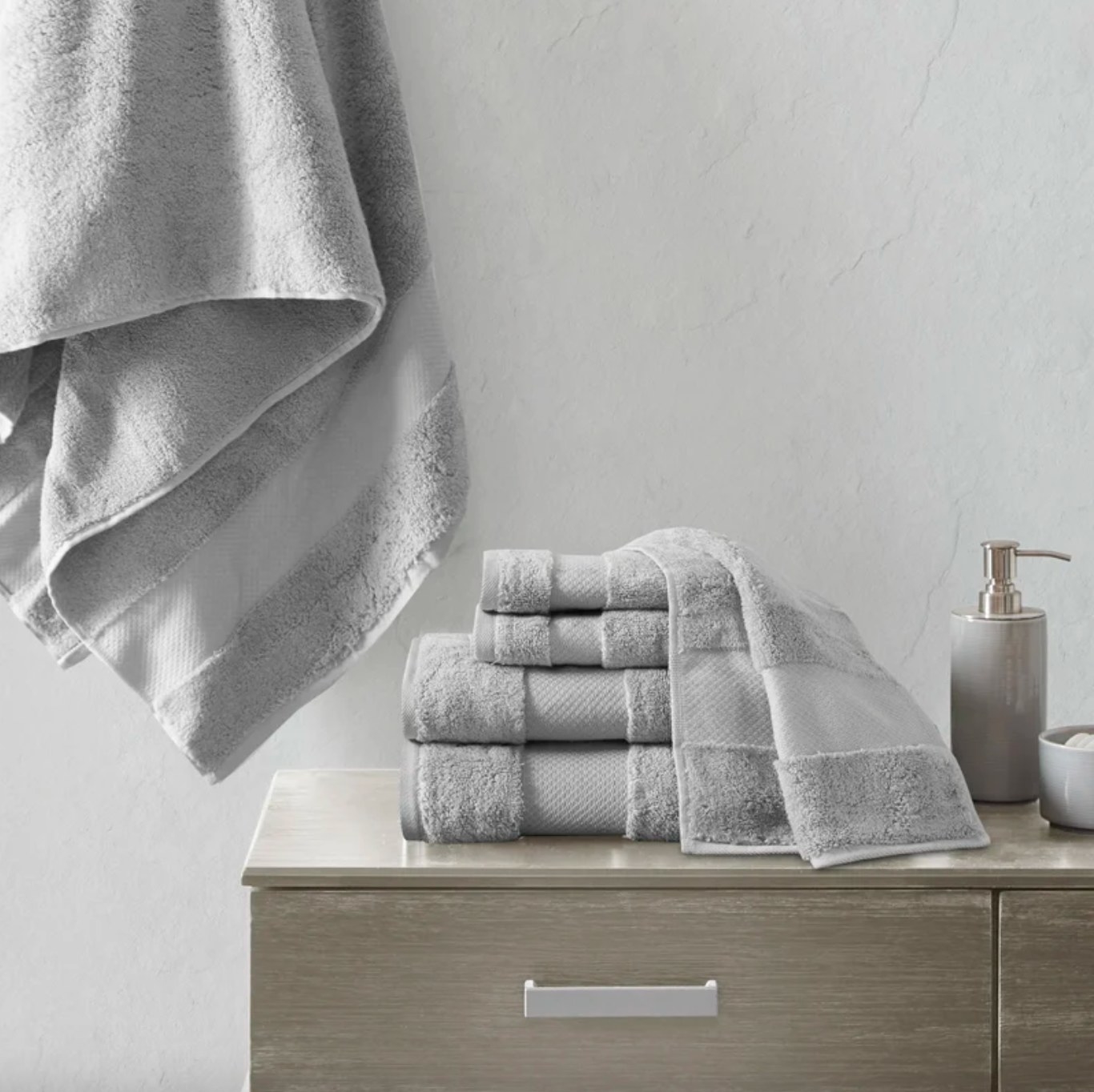 the grey towels stacked on a counter, with one hanging behind